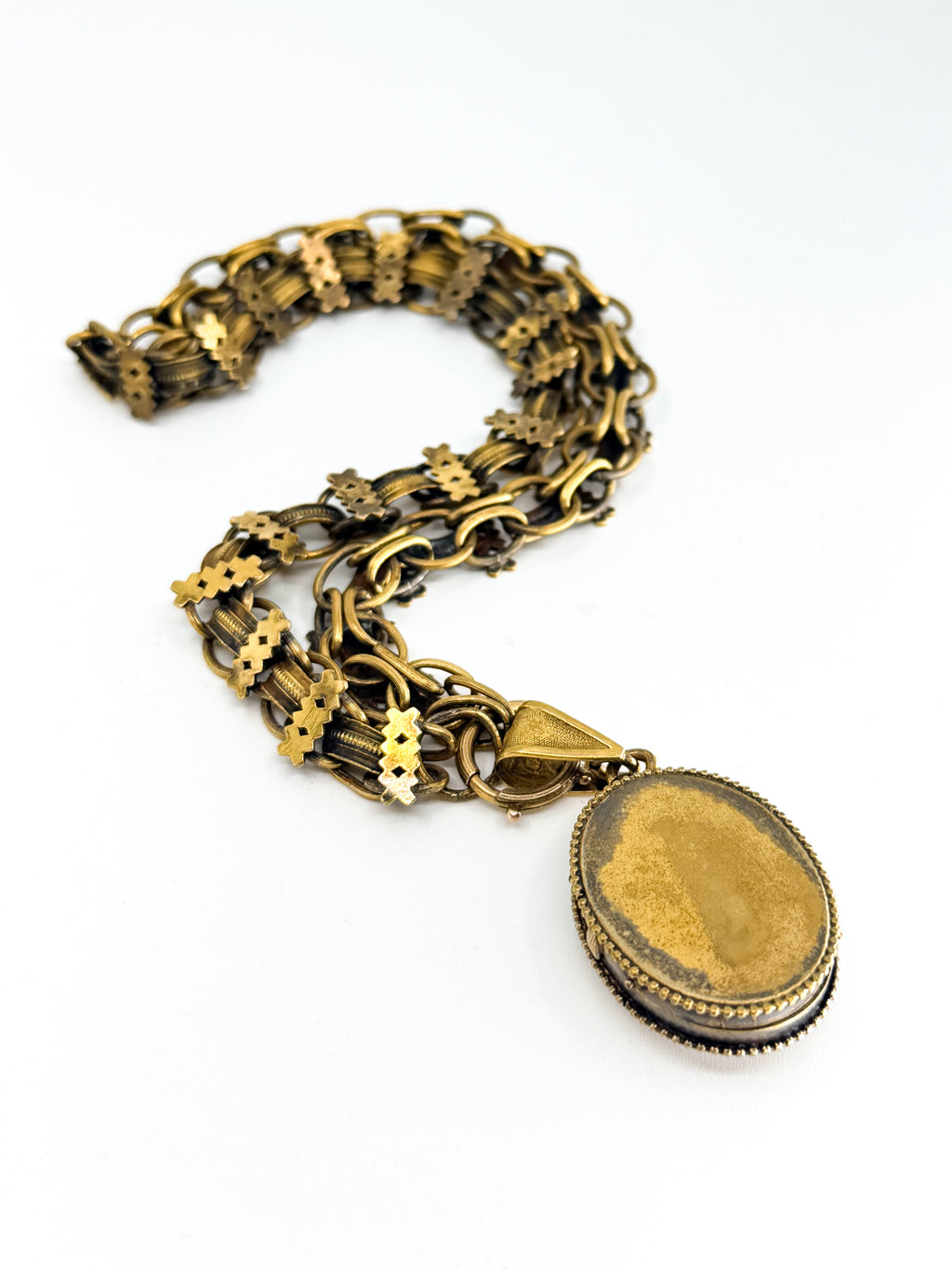 The back of a Victorian locket attached to a book chain necklace